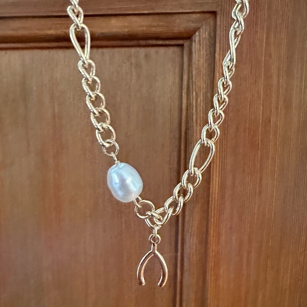 Gold necklace with freshwater pearl and wishbone charm. *Costume jewelry.*